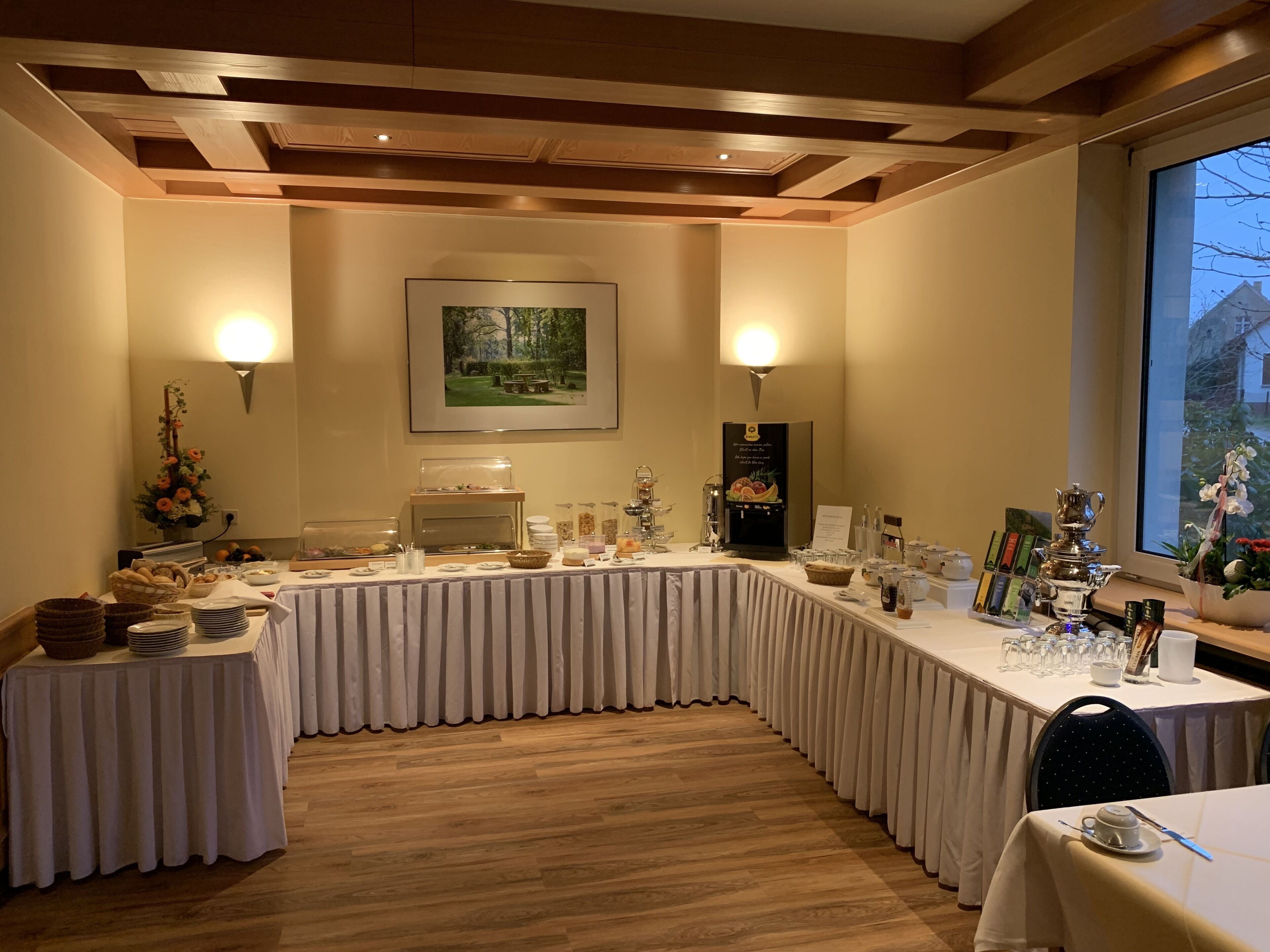 Un salón de conferencias con una larga mesa, servicio tipo buffet y un amplio ventanal.