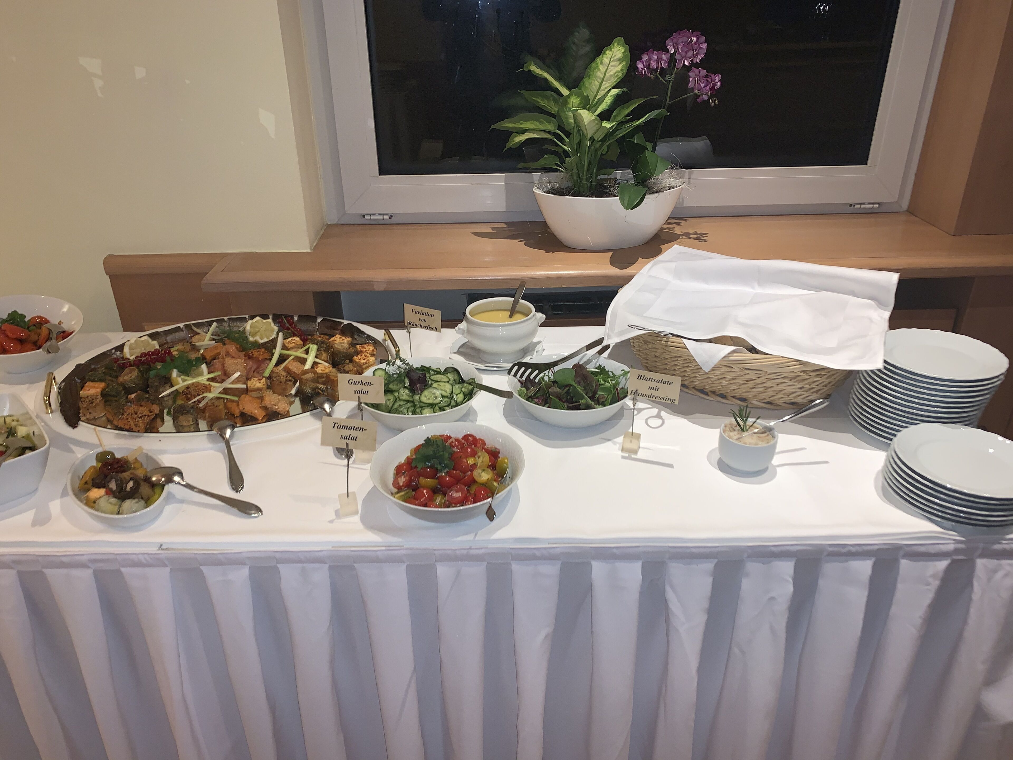 A buffet table with various dishes, including salads, vegetables, and a fish platter.