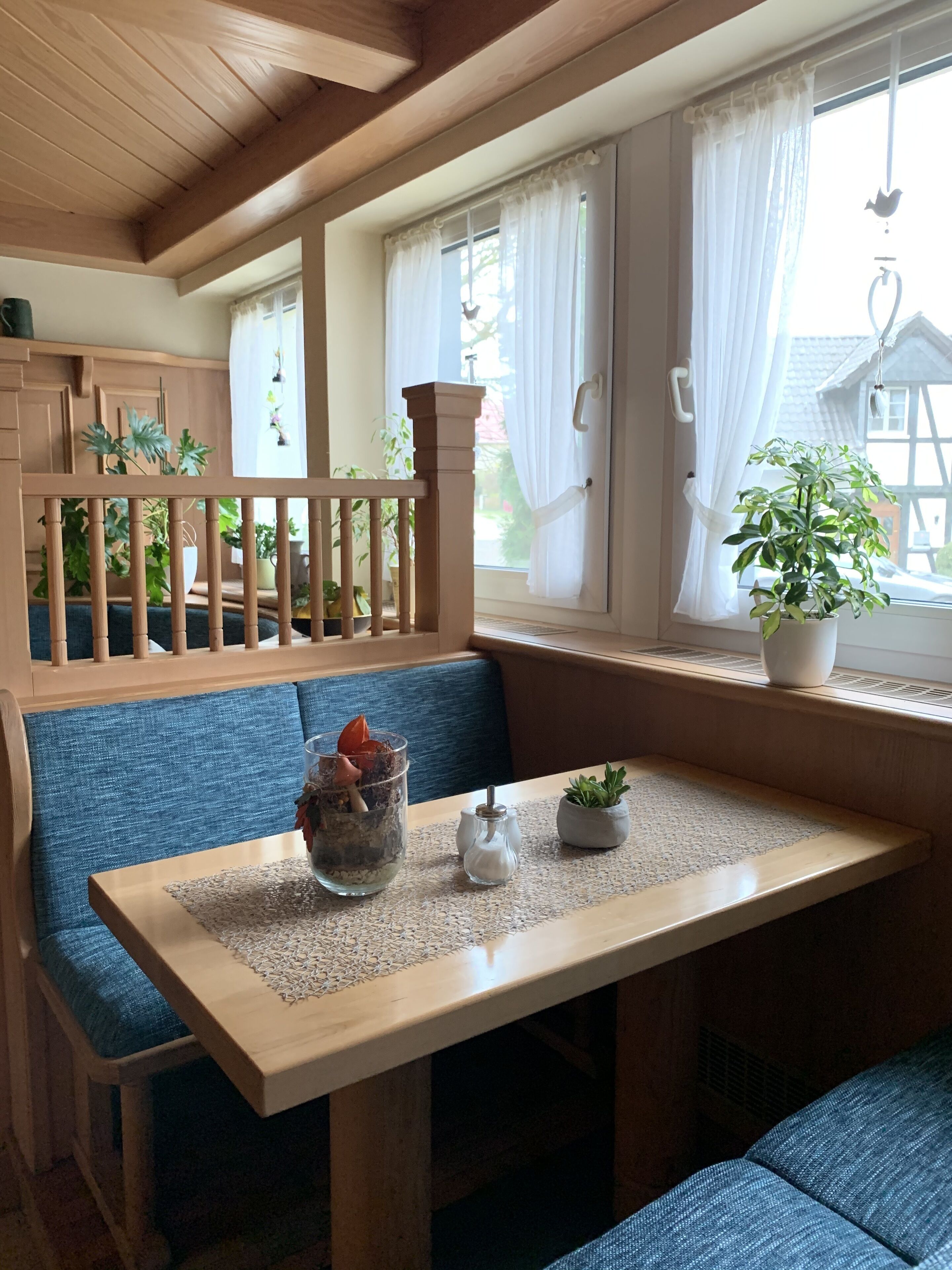 A cozy seating area with a wooden bench, a table with a placemat, and potted plants.