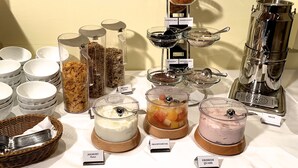 Un bufé con diversos alimentos, entre ellos cereales, frutas y productos lácteos.