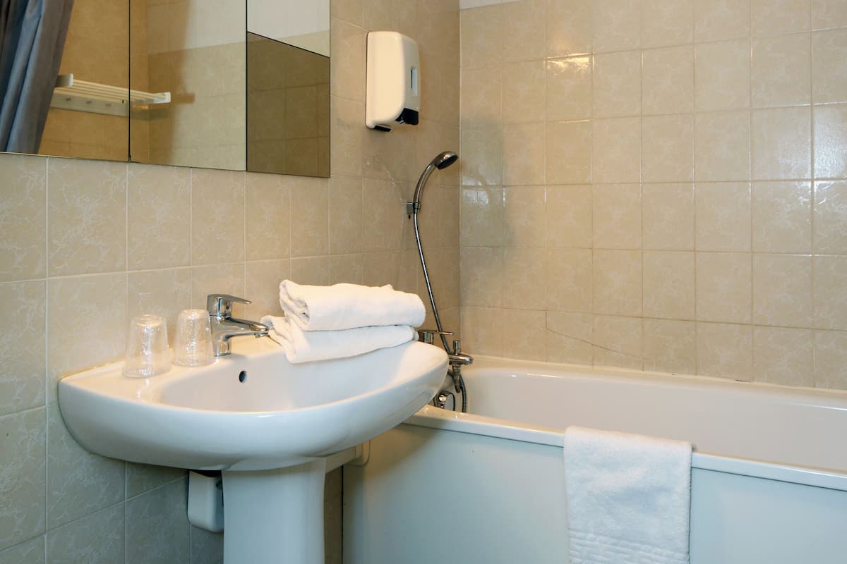 A bathroom with a sink, mirror, towel rack, and a bathtub.