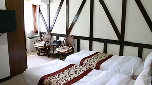 A hotel room with two beds, a television, a desk with a chair, and a window with curtains. - Pension Marie (Yamanakako)