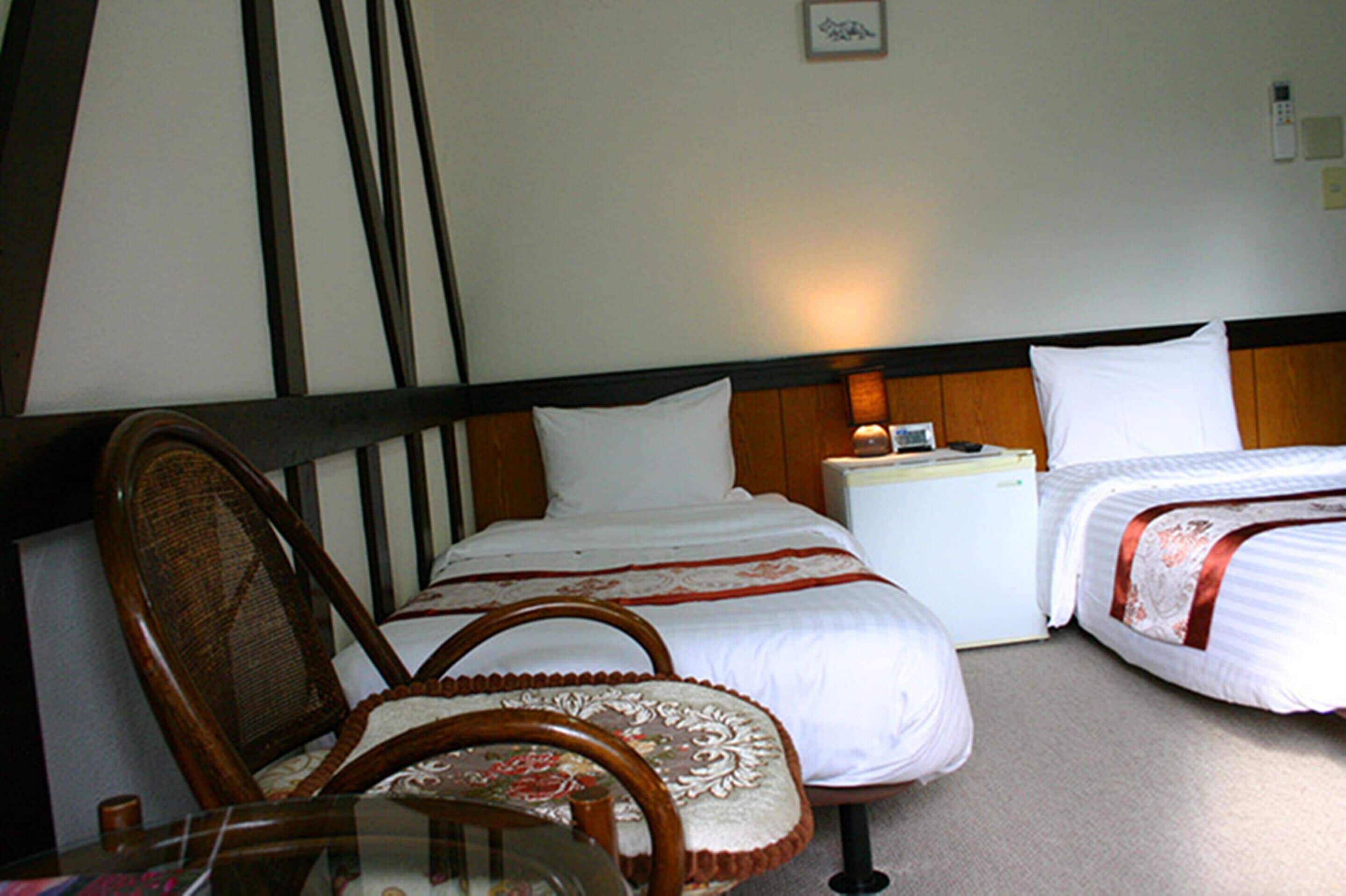 A hotel room with a single bed, a nightstand, a chair, and a small table.