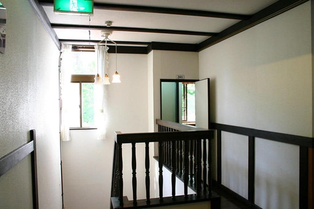 A hallway with a staircase, a visible door number, and a hanging light fixture.