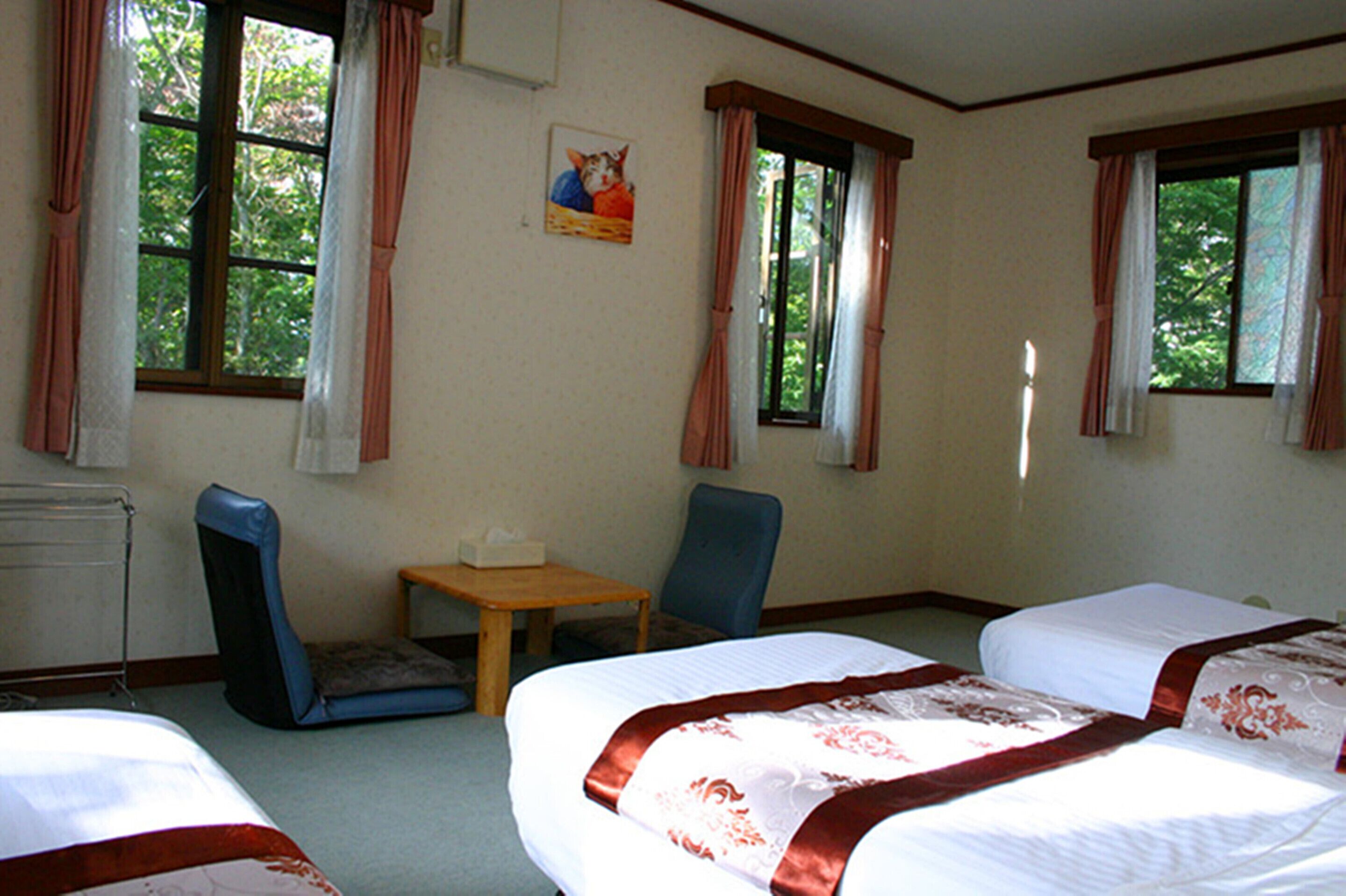 A hotel room with two beds, a desk, a chair, and a window with curtains.