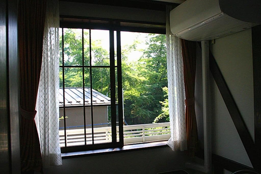 A room with a large window, curtains, and an air conditioning unit.