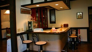 A bar area with a counter, three chairs, and a decorative vase. - Pension Marie (Yamanakako)