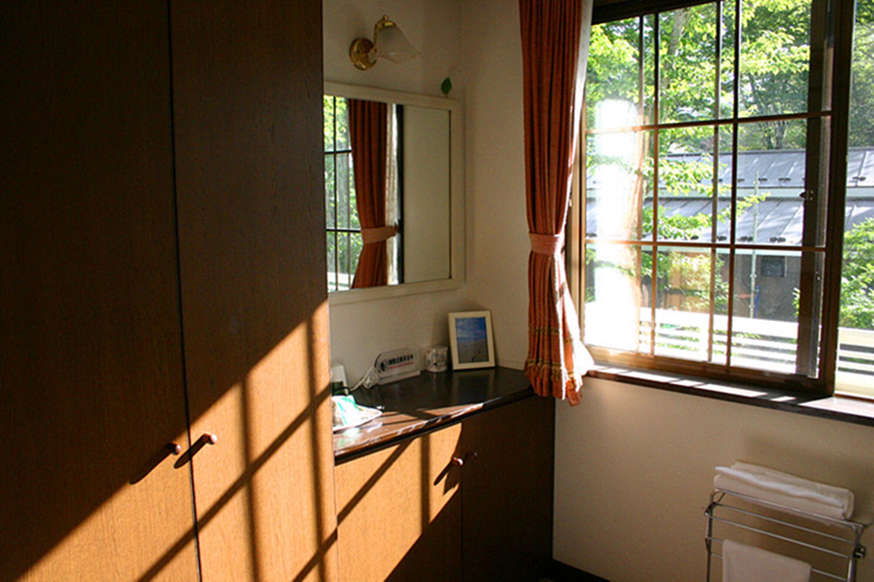 A bathroom with a window, a towel rack, a mirror, and a countertop with a thermometer.