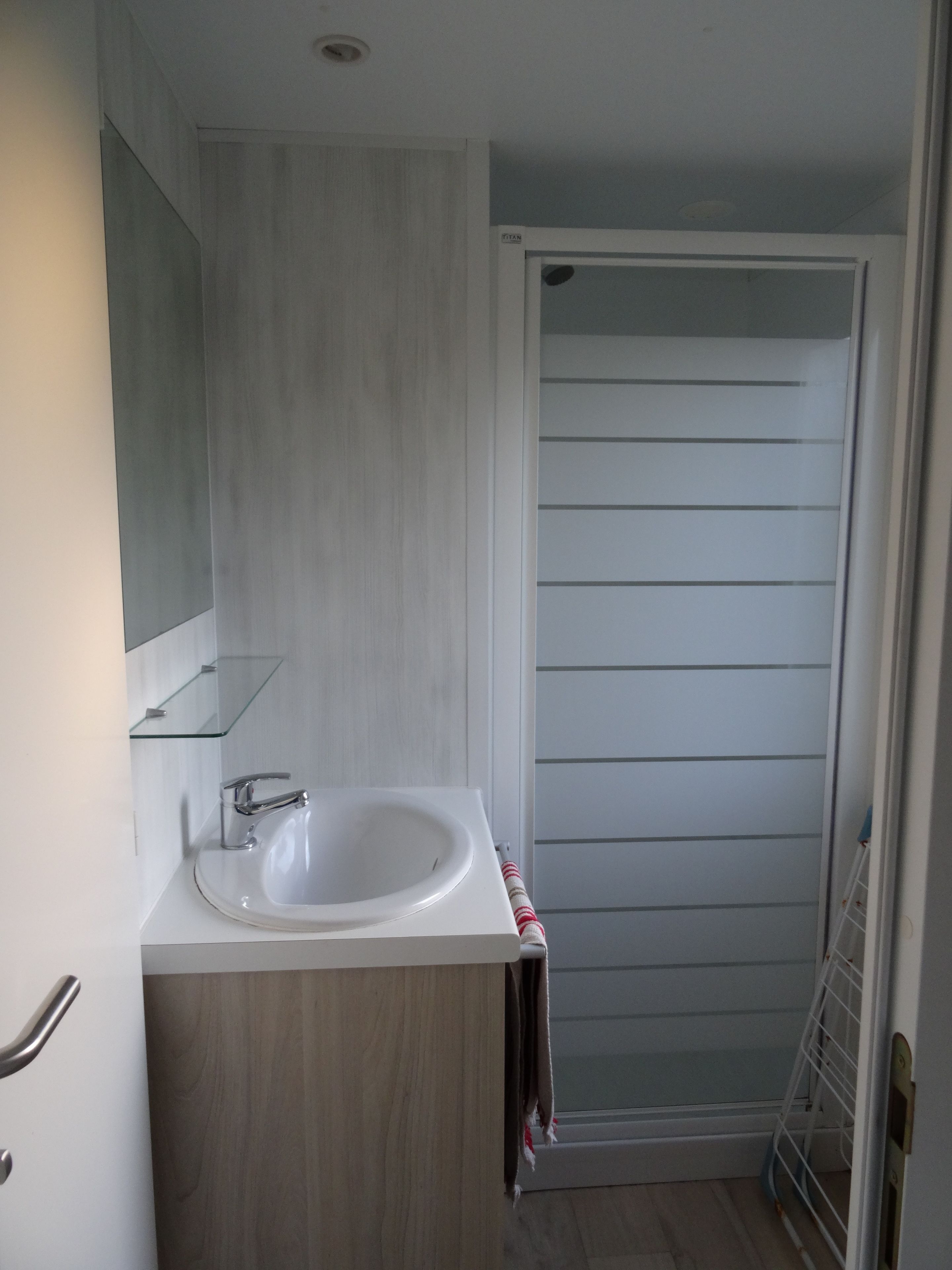 A bathroom with a white sink, a mirror, and a shower door.