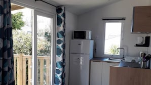 A compact kitchen with a refrigerator, microwave, and sink. There is a dining area with a table and chairs.