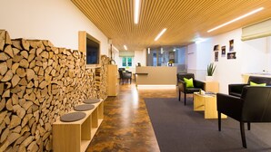 A modern reception area with a wooden wall, seating, and a reception desk. - DIE KRONE - Hotel Garni (Kirchzarten)