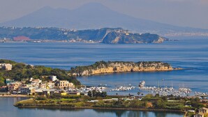 A coastal town with a marina, buildings, and a mountain in the background. - La Rada B&B (Bacoli)