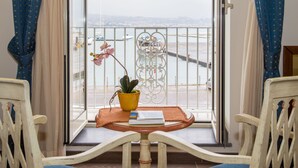 A balcony with a table, chairs, a potted plant, and a view of boats and a cityscape. - La Rada B&B (Bacoli)