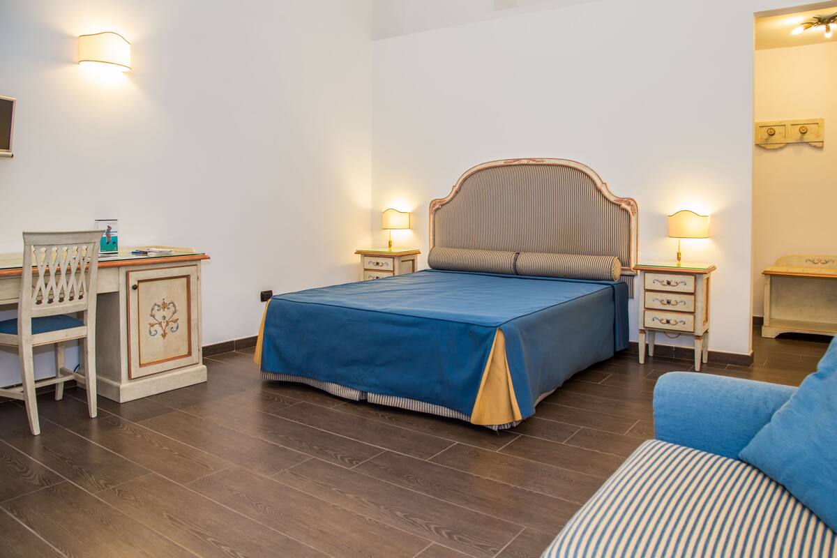 A bedroom with a bed, bedside tables, a desk, and a chair.