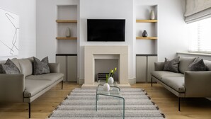 A modern living room with a flat-screen TV, two sofas, a fireplace, and a minimalist decor. - AKA Marylebone (London)