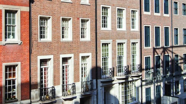 A row of red brick townhouses with white window frames and black railings. - AKA Marylebone (London)