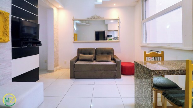 Una sala de estar moderna con un sofá, un televisor, una mesa de comedor y un ventanal grande.