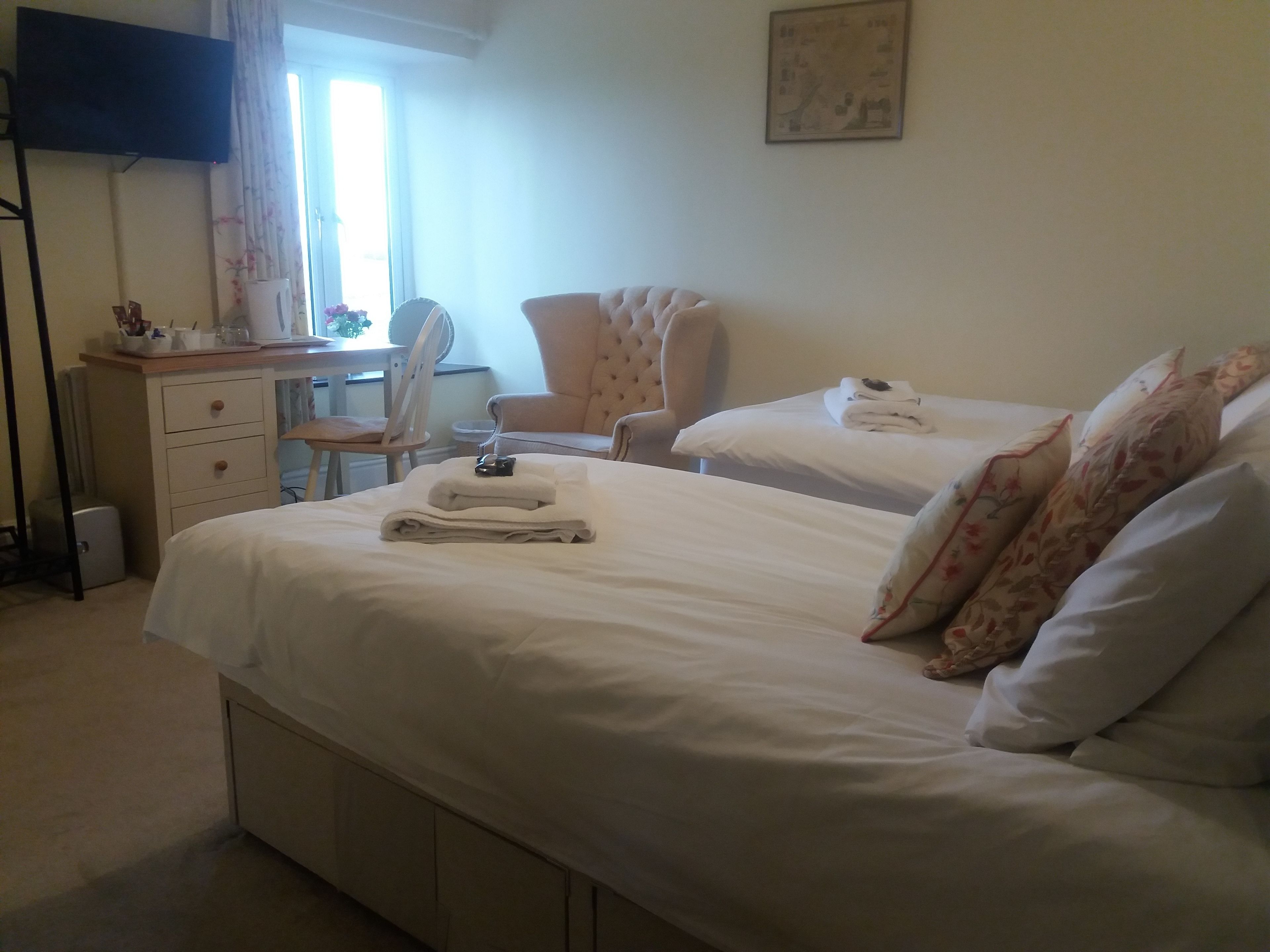 Quarto de hotel com duas camas, uma escrivaninha, uma cadeira e uma televisão.