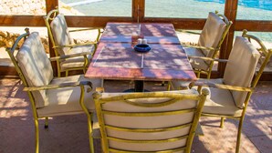 A table and chairs set up on a patio with a view of the ocean and a boat in the distance.