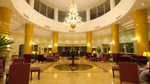 A spacious lobby with a central chandelier, multiple seating areas, and a reception desk.