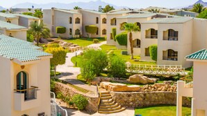 A resort with multiple buildings, a central courtyard with a pathway, and a stone wall.