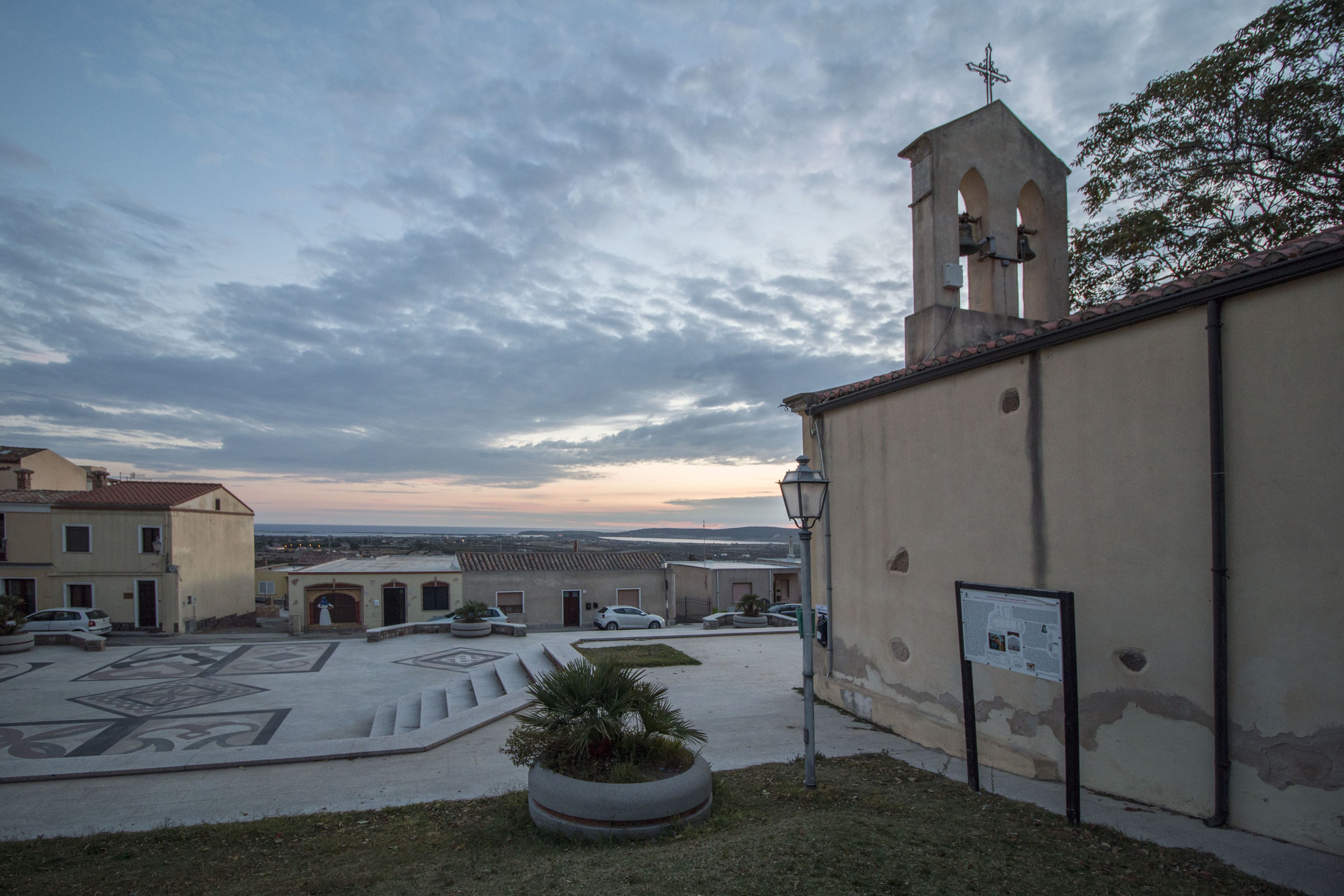 Un pati amb una església, un campanar i una zona pavimentada amb dibuixos geomètrics.