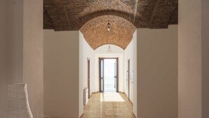 A hallway with a tiled floor, a brick archway ceiling, and a hanging light fixture. - Villa Santadi Hotel (Santadi)
