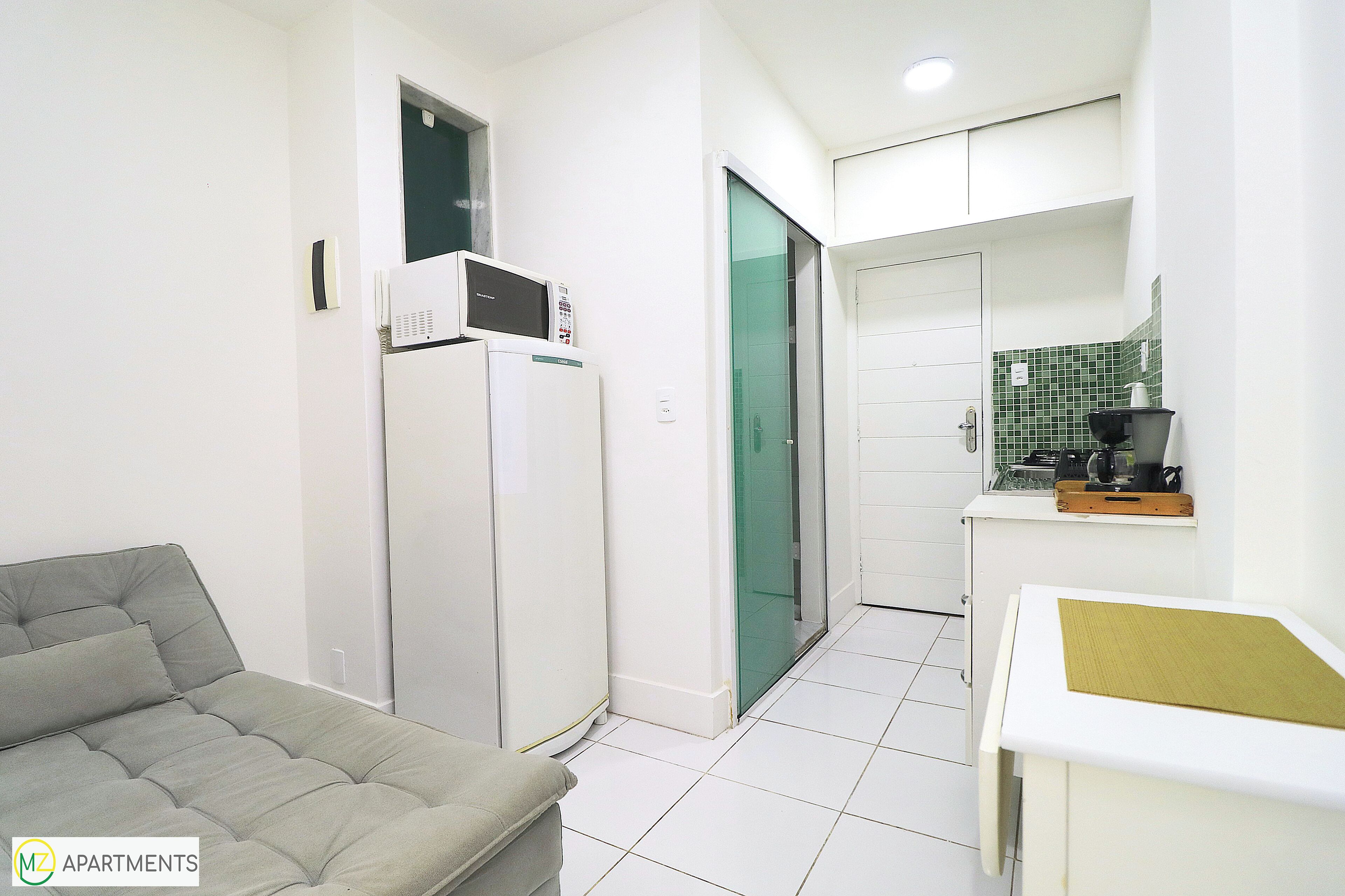 A compact living space with a kitchenette, a sofa, and a small dining table.