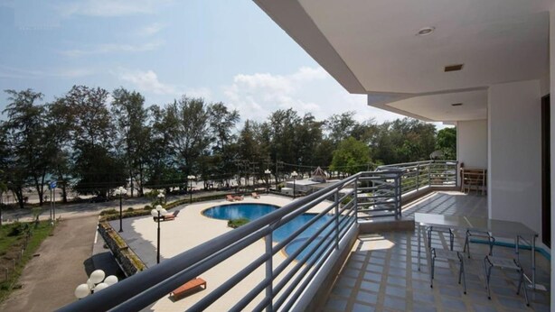 A balcony with a view of a swimming pool and surrounding trees. - Rayong by Milanee (Rayong)