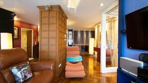 A modern living room with a brown leather sofa, a wooden cabinet, and a blue wall with a flat-screen TV. - Rayong by Milanee (Rayong)