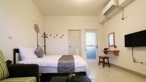 A hotel room with a bed, a sofa, a coffee table with a plant, a TV, and a door leading to another room. - The Green Mile Field B&B (Ji'an)