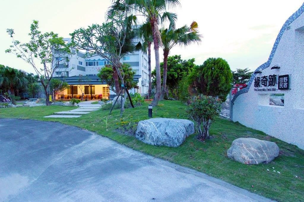 A modern building with a well-maintained lawn, large rocks, and a pathway leading to the entrance.