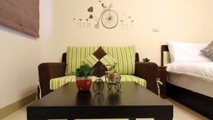 A modern living room with a sofa, a small table with decorative items, and a wall art piece. - The Green Mile Field B&B (Ji'an)