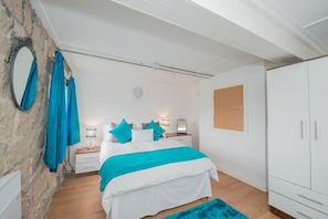 A bedroom with a bed, a nightstand, a lamp, a mirror, and a wardrobe.