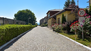 A cobblestone street lined with buildings, a speed limit sign, and a sign indicating a territory. - Bojur & Bojurland Apartment Complex (Bansko)