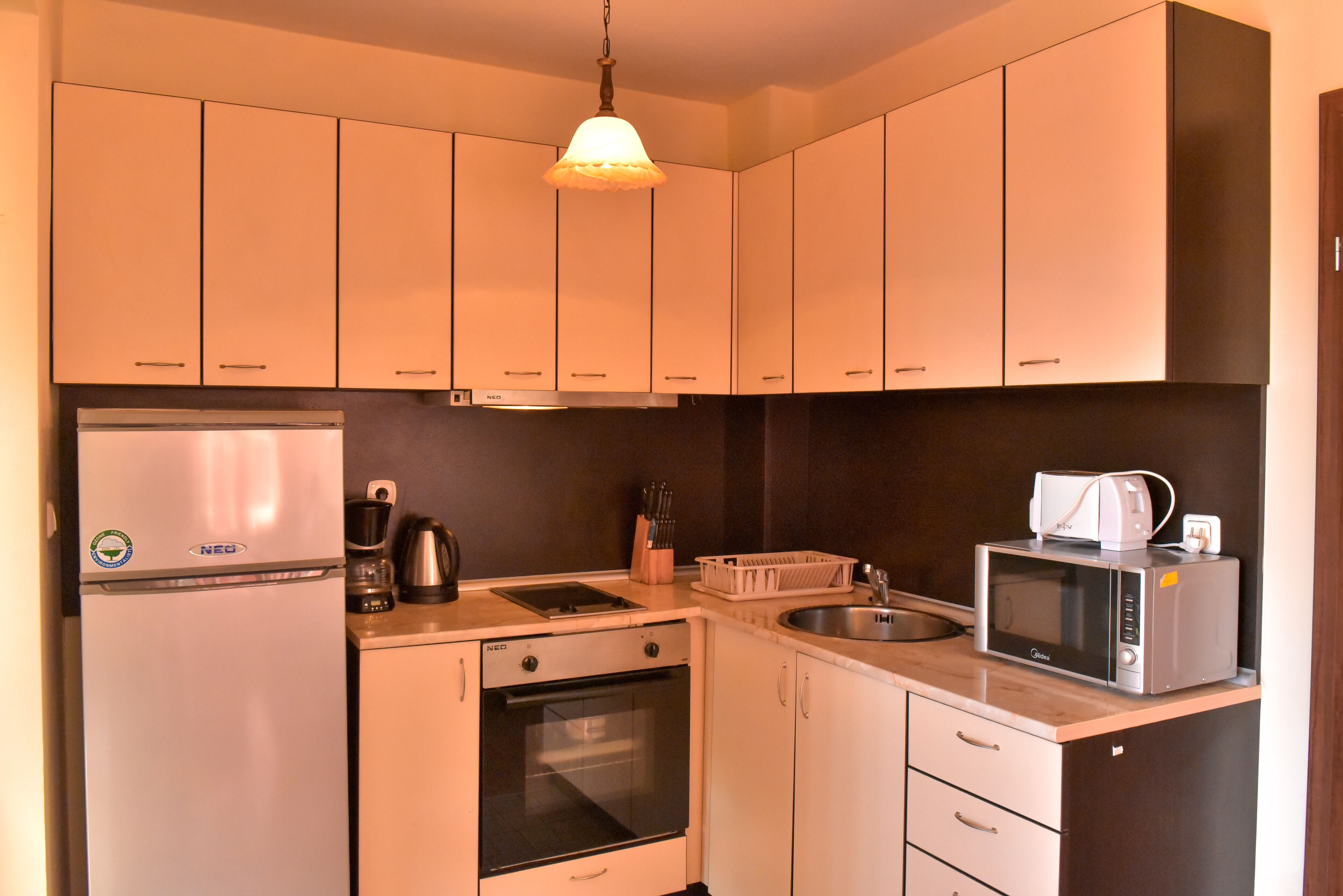A compact kitchen with a refrigerator, oven, microwave, and a coffee maker.