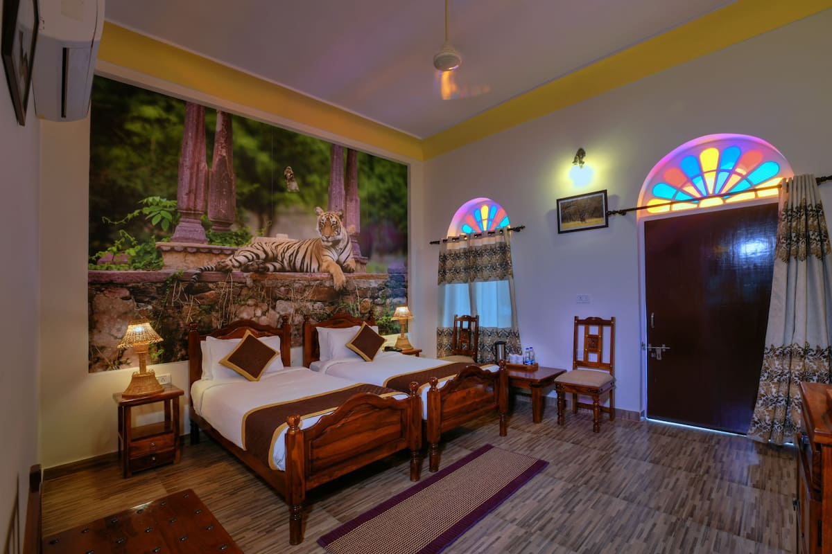 A bedroom with a bed, two nightstands, a chair, a desk, a door, and a window with a tiger mural.
