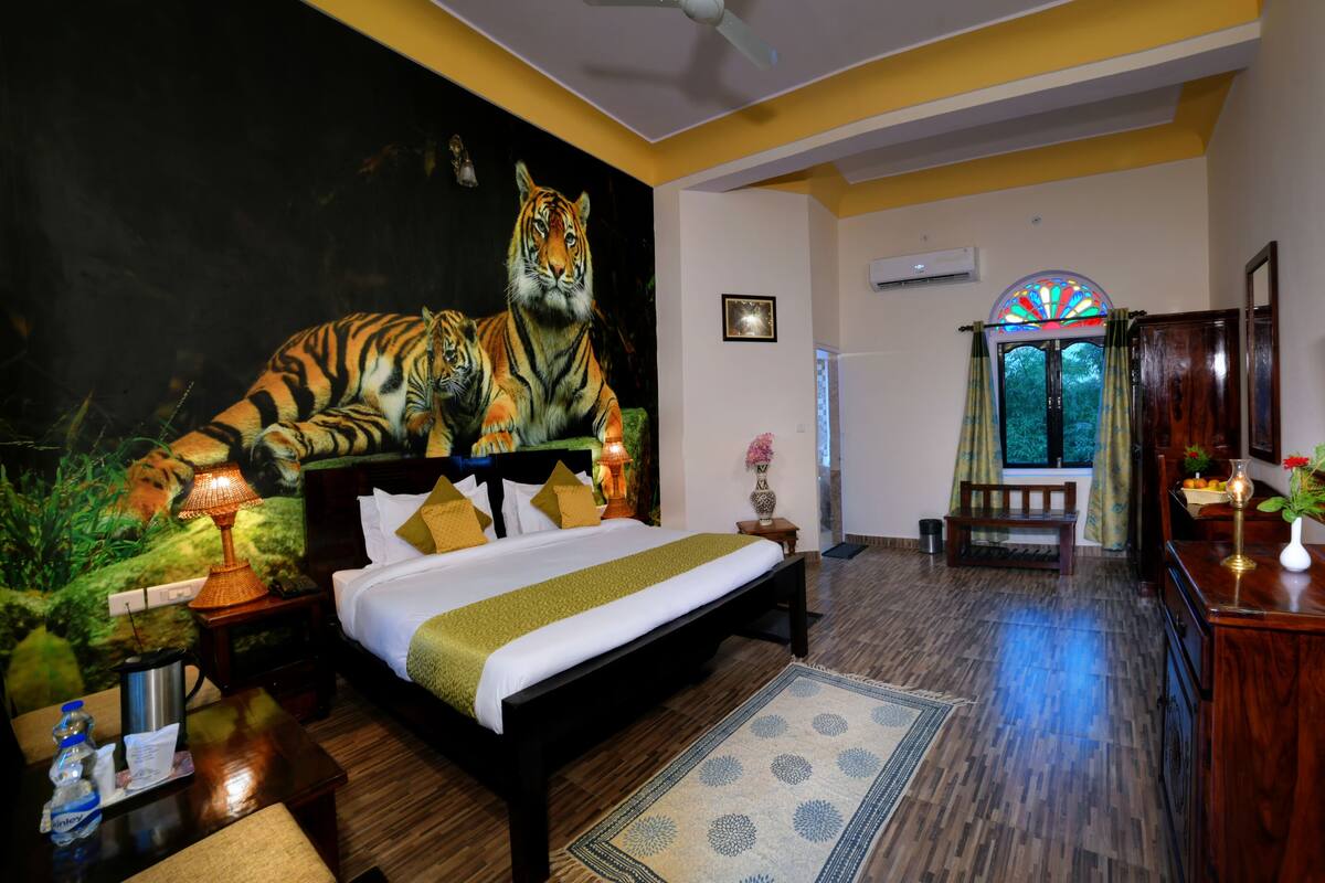 A bedroom with a tiger mural, a bed, a TV, and a wooden floor.