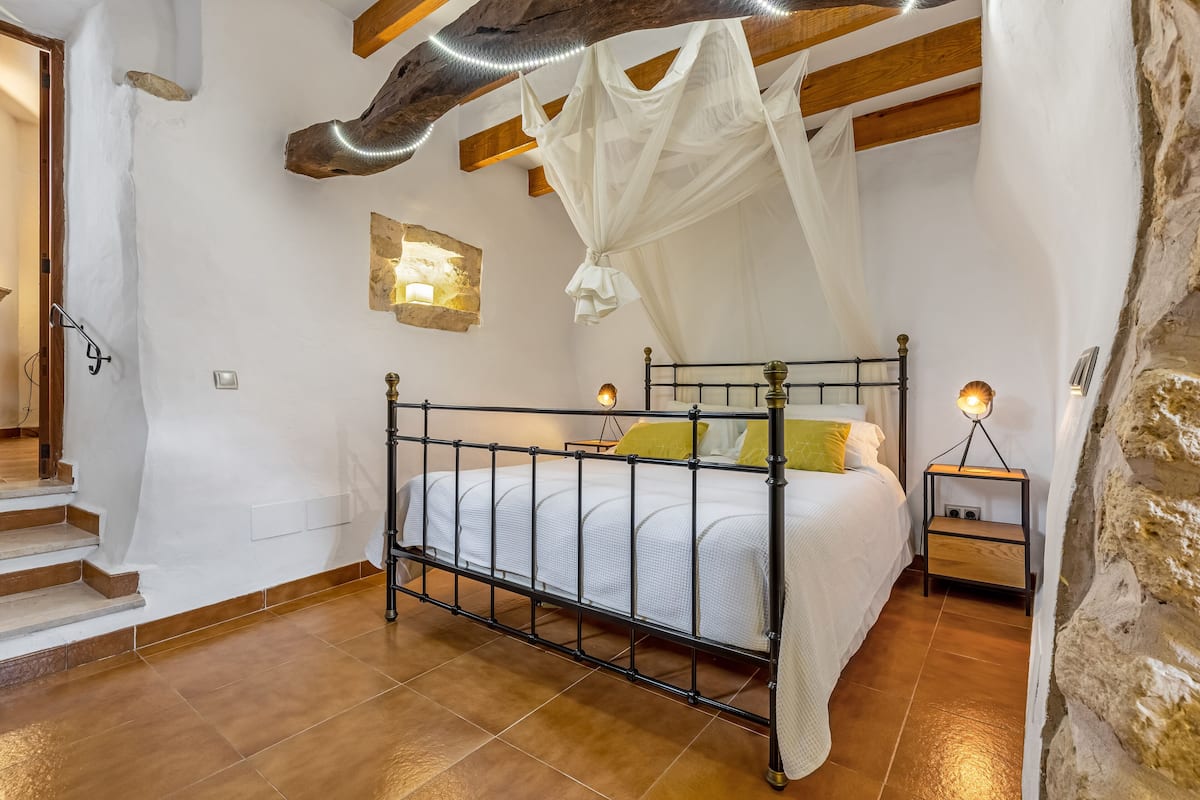 Quarto com cama, mesas de cabeceira e escada.