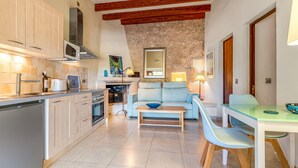 Une cuisine compacte dotée d’appareils électroménagers modernes, un coin repas avec une table et des chaises, et un espace salon confortable avec un canapé et un miroir.
