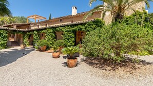 A courtyard with a stone building, potted plants, and a pergola. - Finca Son Jorbo (Porreres)