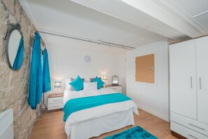 A bedroom with a bed, a nightstand, a lamp, a mirror, and a wardrobe.