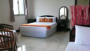 A hotel room with a bed, a wooden chair, a small table, and a mirror. - Guoguang B&B (Hualien City)