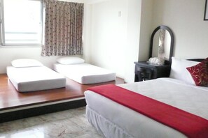 A hotel room with a bed, two single beds, a mirror, and a window with curtains. - Guoguang B&B (Hualien City)