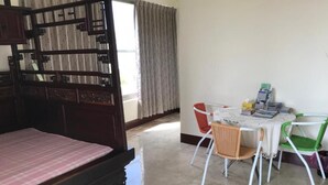 A room with a bed, a table with chairs, and a window with curtains. - Guoguang B&B (Hualien City)