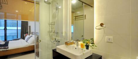 A modern bathroom with a glass shower enclosure, a white sink with a black countertop, and a visible toilet.