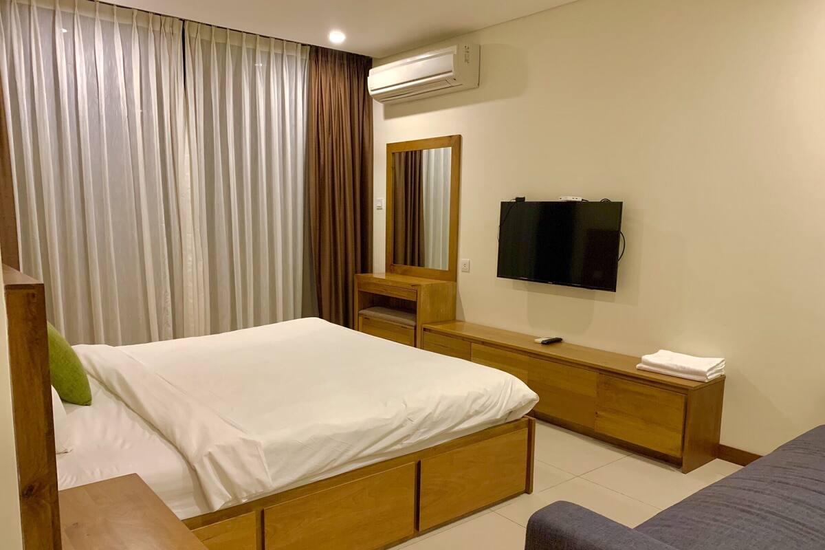 Une chambre d’hôtel avec un lit, une télévision, une commode en bois et un canapé.