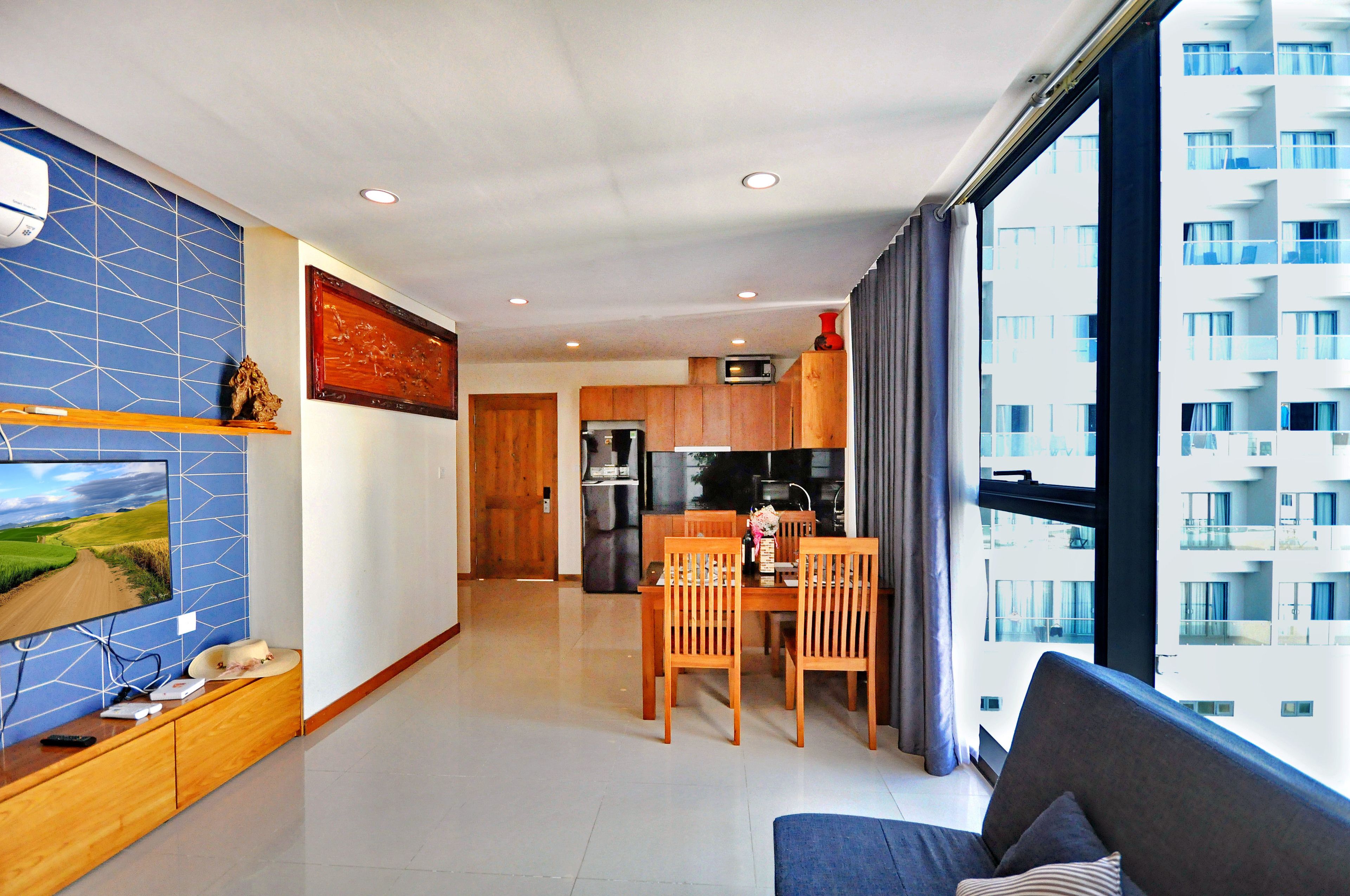 Un appartement moderne comprenant un coin repas, une cuisine et une grande fenêtre donnant sur un immeuble de grande hauteur.