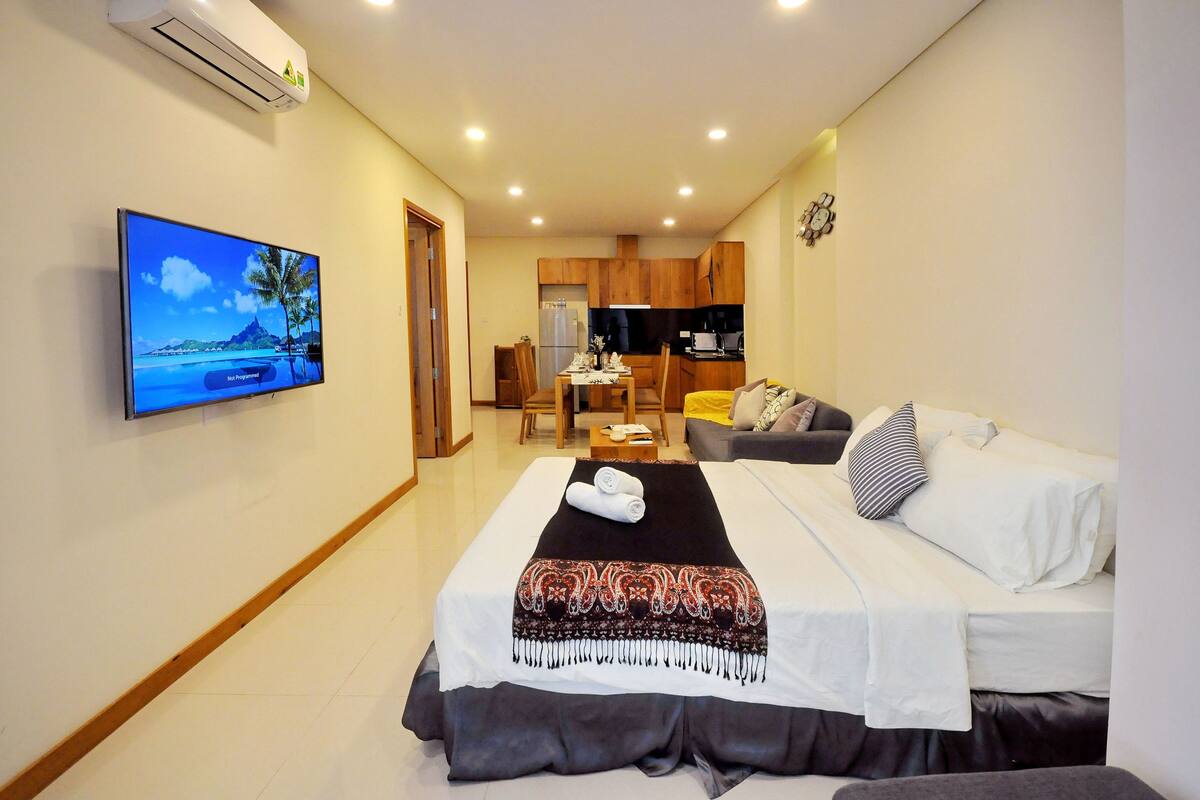 Une chambre d’hôtel équipée d’un lit, d’une télévision, d’un canapé et d’une kitchenette.