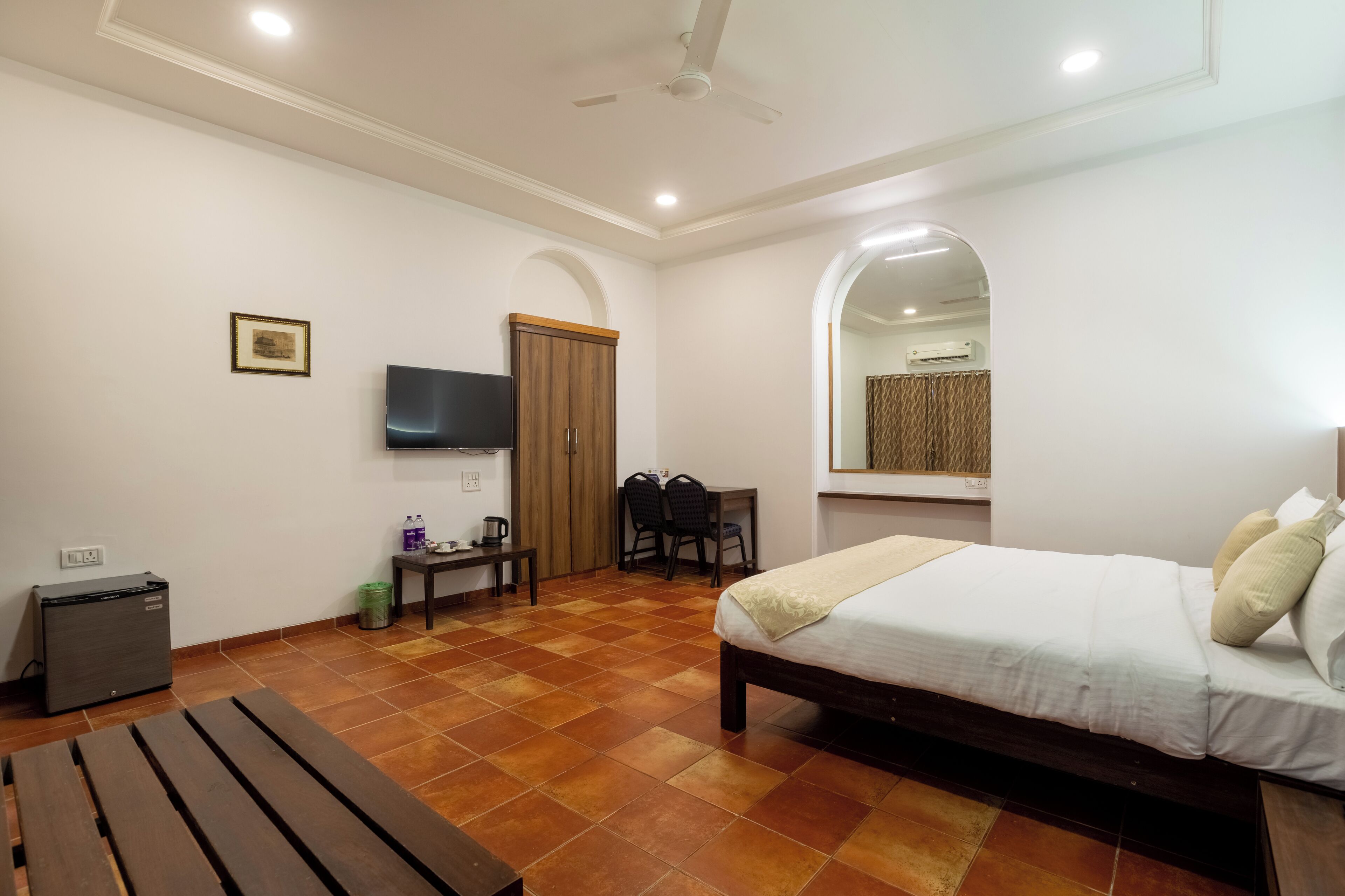 A bedroom with a bed, a desk, a chair, a TV, and a ceiling fan.